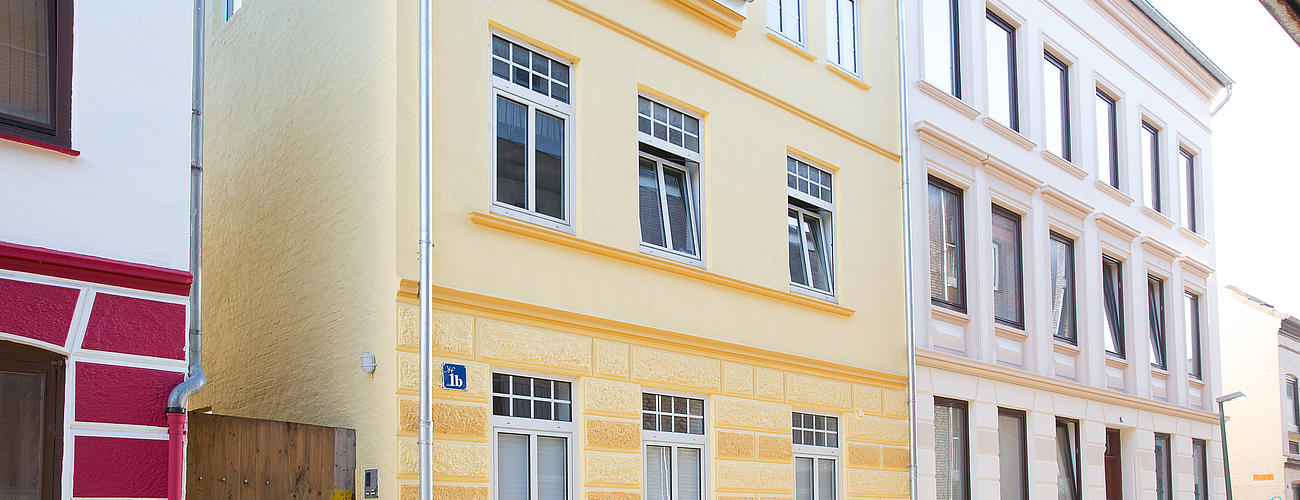 Ansicht von links auf das gelbe Gebäude in der Mittelstraße 1b.
